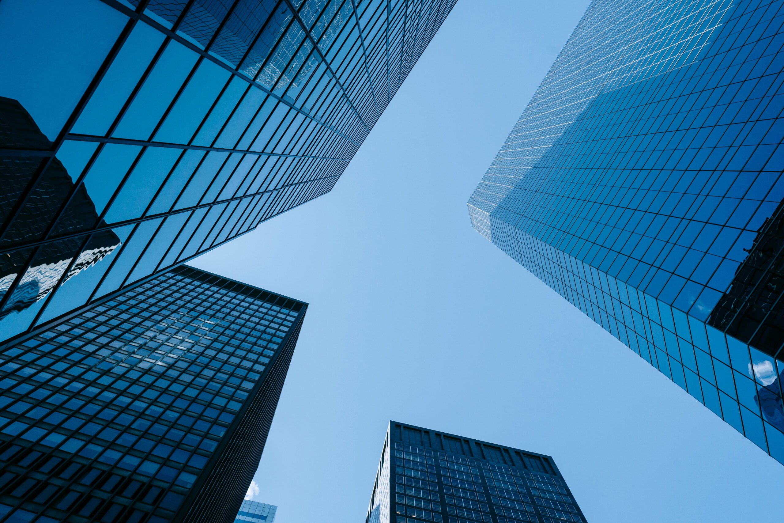 From below of contemporary high rise buildings with glass walls located on street with sunlight in modern district of city